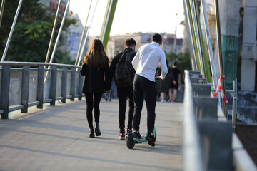Mężczyzna jedzie na hulajnodze po moście we Wrocławiu. - obrazy, fototapety, plakaty