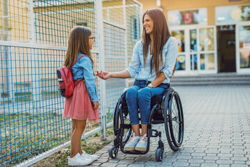 A mother in a wheelchair takes her daughter to school.