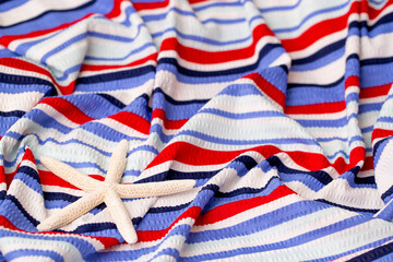 The surface of the bed linen at the resort with starfish. Close-up of soft multicolored wave patterns, fabric texture as background. Sea vacation, beach season. Towel on a sun lounger.