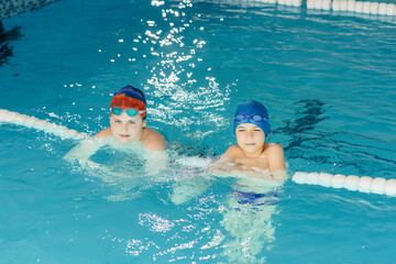 A group of boys and girls train and learn to swim in the pool with an instructor. Development of children's sports.