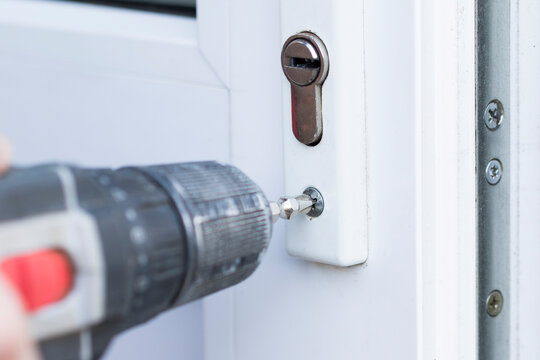 Handyman check door lock with screw gun in front door. Checking lock for operability close up.