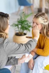 Woman psychologist wipes tears of teenage girl with paper handkerchief. Emotional intelligence and...