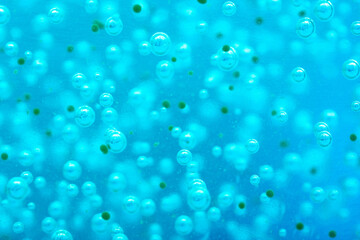 Liquid with bubbles. Close-up blue body scrub, particles of exfoliating ingredients, bubbles. Shower gel, cleansing the face and body. Spa treatments, skin care.