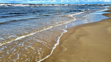 Sandy seashore and blue sky with slight white clouds on a hot summer day