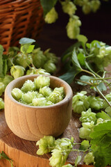Hops flowers in a wooden bowl on rustic background, natural material for brewery production and sourdough bread making,  closeup, natural medicine and naturopathy concept