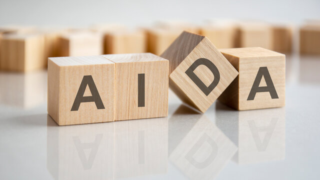 four wooden cubes with the letters AIDA on the bright surface of a gray table, business concept