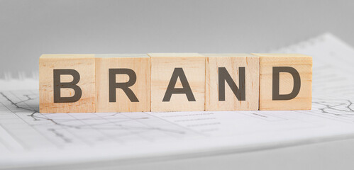 brand is written on light wooden blocks. the word is located on a sheet with charts and graphs