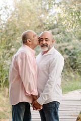 Obraz premium Lovely middle-aged gay couple enjoying romantic moments together during a date. LGBT pride concept.