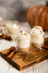 Hot and aromatic latte with pumpkin and cinnamon on a concrete textured wood background, copy space.