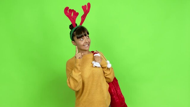 Young woman with christmas hat pointing a great idea and looking up over isolated background. Green screen chroma key