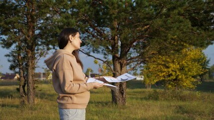 Sad woman with dark hair in beige hoodie sighs heavily and gives poster of missing cat to man passerby in green park on sunny day, side view
