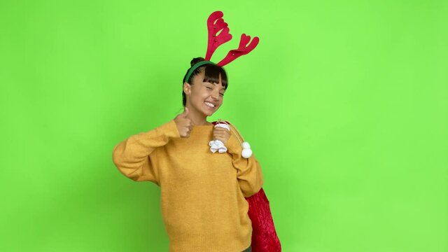 Young woman with christmas hat giving thumbs up and smiling because something good has happened over isolated background. Green screen chroma key