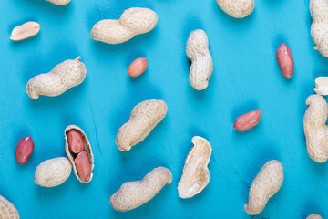 fresh peanuts in a shell on a bright blue slate, concrete or stone background. lots of nuts. the concept of proper nutrition. top view.