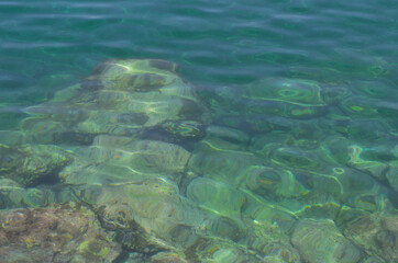 Fototapeta na wymiar Stones and corals under water, glare on the sea surface