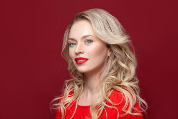 Perfect model blonde woman smiling and looking at camera on red background