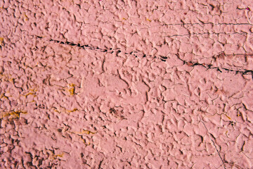 Old iron wall, relief surface, cracked pink paint with rust and black stripe.