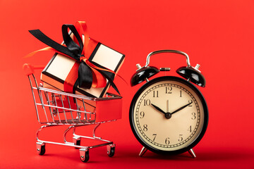 red basket with a gift box and an alarm clock on a red background.with copy space shopping time