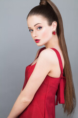 Beautiful glamorous woman fashion model with pony tail hairstyle wearing red dress and golden...