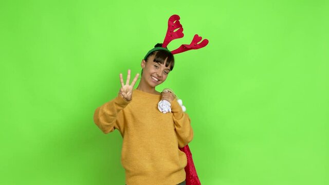 Young woman with christmas hat happy and counting with fingers over isolated background. Green screen chroma key