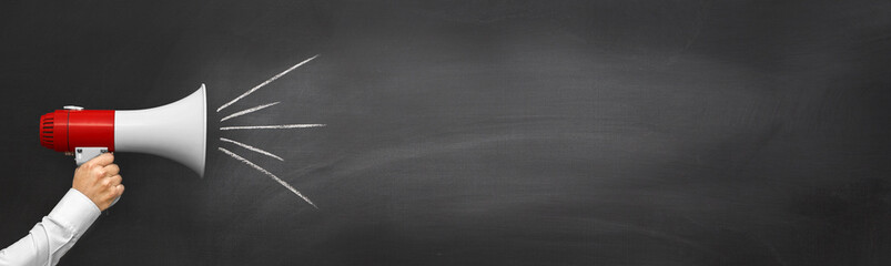 Hand with a megaphone in front of an empty blackboard - obrazy, fototapety, plakaty