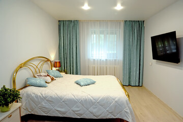 Bedroom interior in light tones with TV on the wall