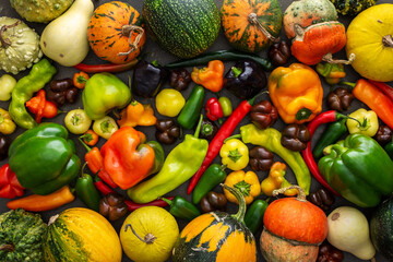 Different types of bitter and sweet peppers and decorative and edible pumpkins, autumn vegetable background, organic healthy farm products