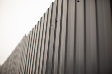 Grey fence made of metal. Solid high fence. Profiled metal is used in the fence of private territory.