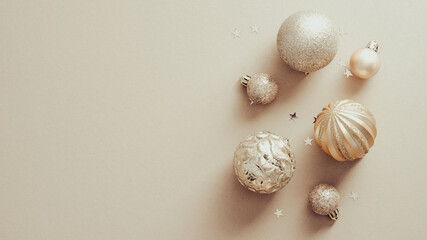 Christmas banner with golden balls decorations on beige background. Flat lay, top view.