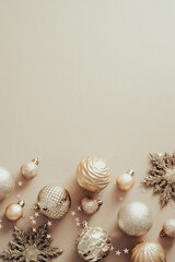 Elegant Christmas poster mockup with golden balls decorations and snowflakes on pastel beige background. Flat lay, top view.