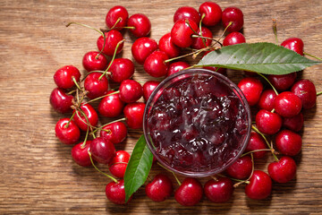 bowl of cherry jam with fresh fruits on a wooden background