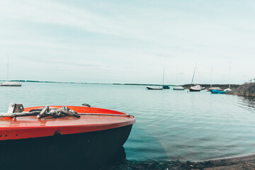 Fototapeta premium A wooden boat stands on the bank of the river. Walking on the water. Boat on the beach in summer by the river. Summer vacation on the water with a boat.