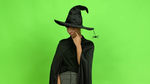 Young woman wearing witch hat for halloween parties looking front over isolated background. Green screen chroma key
