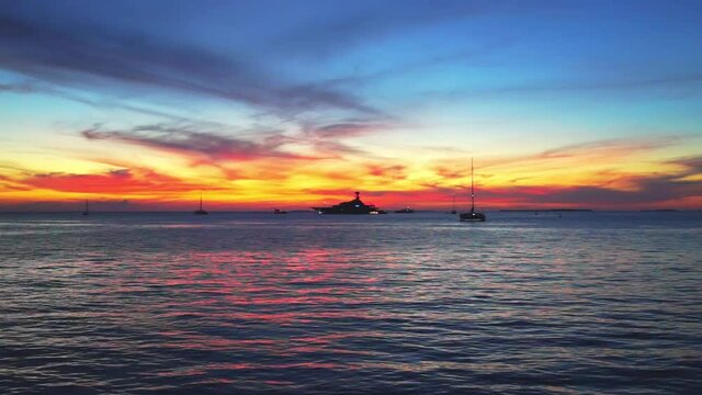 Silhouettes of boats at colorful sunset twilight blue hour with landscape view on red blue cloudy sky reflection in water by Mallory Square of Key West, Florida