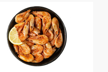 Appetizing shrimps with lemon in a portioned cast iron pan. Healthy food and diet. Isolated on white background. Space for text.