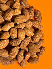 Peeled almond nuts on orange background