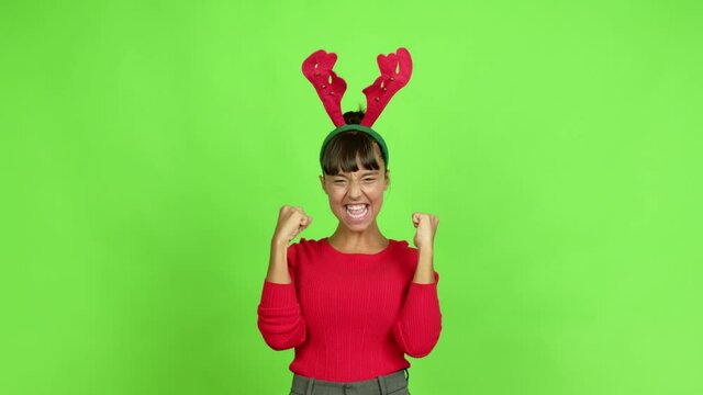 Young woman wearing christmas hat celebrating a victory and surprised to be successful over isolated background. Green screen chroma key