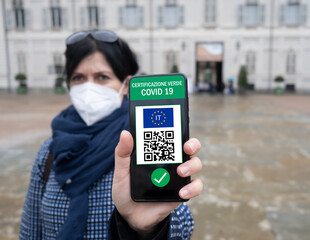 Young Italian woman holding smartphone with Green Pass QR code confirm vaccination coronavirus covid-19. Vaccine done with passport