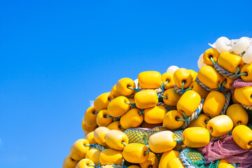 Heap of yellow fishing net floats on the blue sky background. fishing industry. Yellow fishing bobbers. © senerdagasan