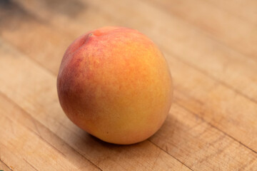 A single ripe Angelus peach on wooden carving board 