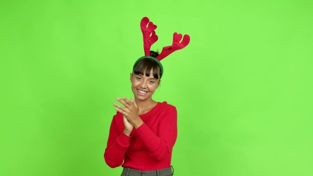 Young woman wearing christmas hat applauding after presentation in a conference over isolated background. Green screen chroma key