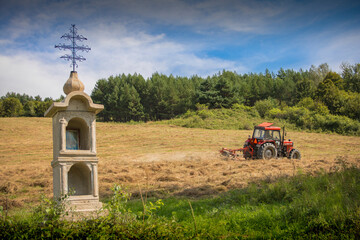 Little Chapel and red tractor located in Podkarpacie Poland (Beskid Niski Mountains) 