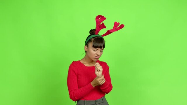 Young woman wearing christmas hat with pain in hand over isolated background. Green screen chroma key