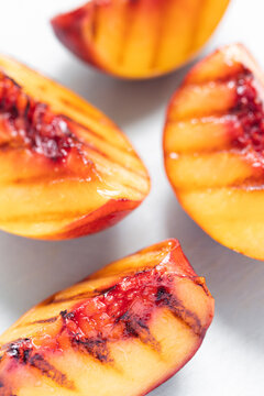 Juicy grilled nectarine quarters on light gray cutting board. Top view. Selective soft focus. Abstract food background.