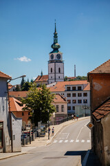 Fototapeta premium Trebic, Bohemia, Czech Republic, 06 July 2021: Narrow picturesque street with colorful buildings in historic center, renaissance and baroque medieval city, Church of St. Martina at sunny summer day