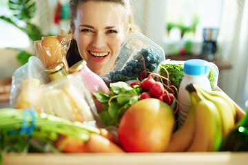 happy modern housewife with food box in kitchen