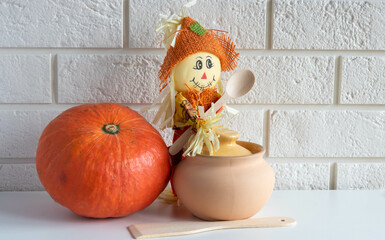 A scarecrow with a wooden spoon,a clay pot and a pumpkin on a white background.Halloween and Thanksgiving Day Concept