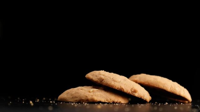 Super slow motion of stack of cookies falling on table on black background.
