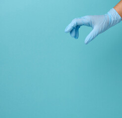 Doctor's hand in a blue medical glove holds an object on a blue background
