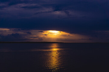 Obraz premium Golden Sunset In Storm Clouds Over Ocean Lake