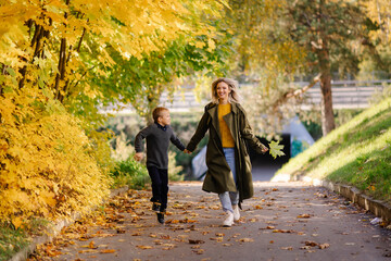 Mother and son have fun together. Family walk in the park in autumn. Hello October. Thanksgiving holiday. Happy motherhood. Childhood. Maple leaves. Fun play together. Fall. Mother's love